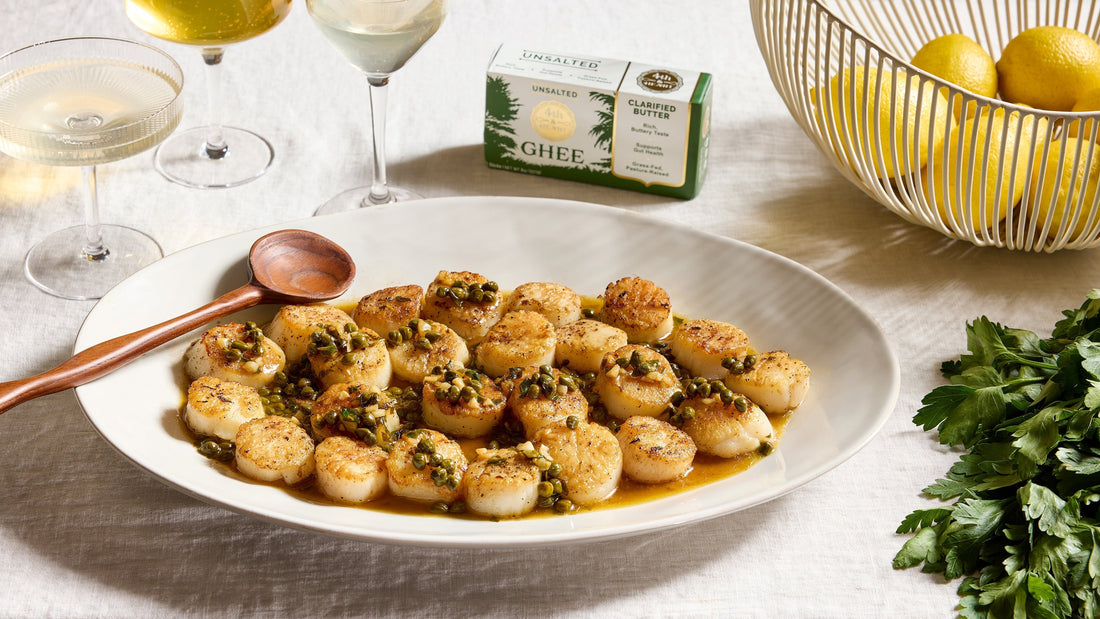 Seared Scallops with Lemon Caper Ghee Sauce on a serving platter next to 4th & Heart butter sticks.