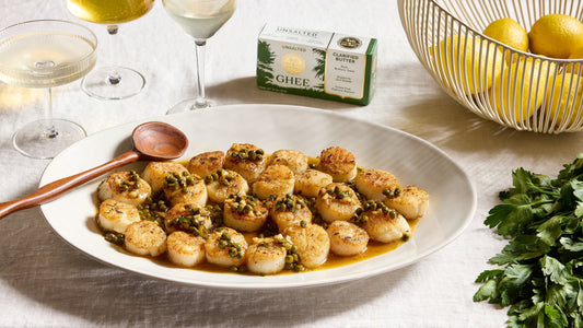 Seared Scallops with Lemon Caper Ghee Sauce on a serving platter next to 4th & Heart butter sticks.