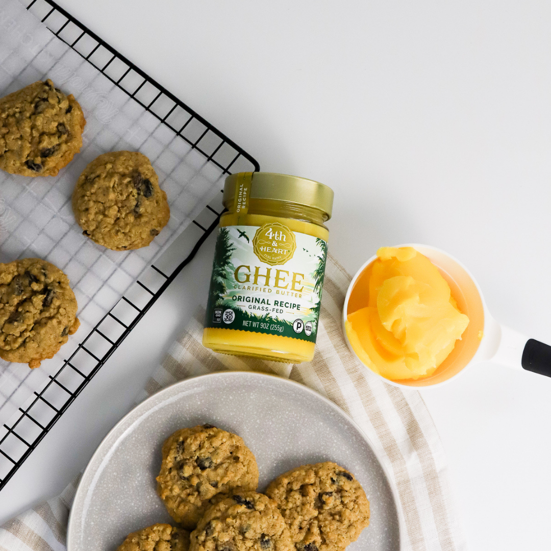 4th & Heart Ghee Butter next to Oatmeal Raisin Cookies on a plate and on a cookie drying rack