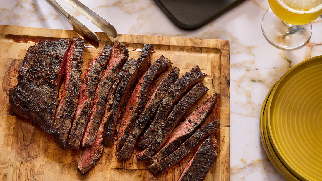 Pepper-Crusted Flank Steak sliced and resting on a cutting board.