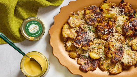 Roasted Smashed Potatoes on a serving platter next to a jar of 4th & Heart ghee.