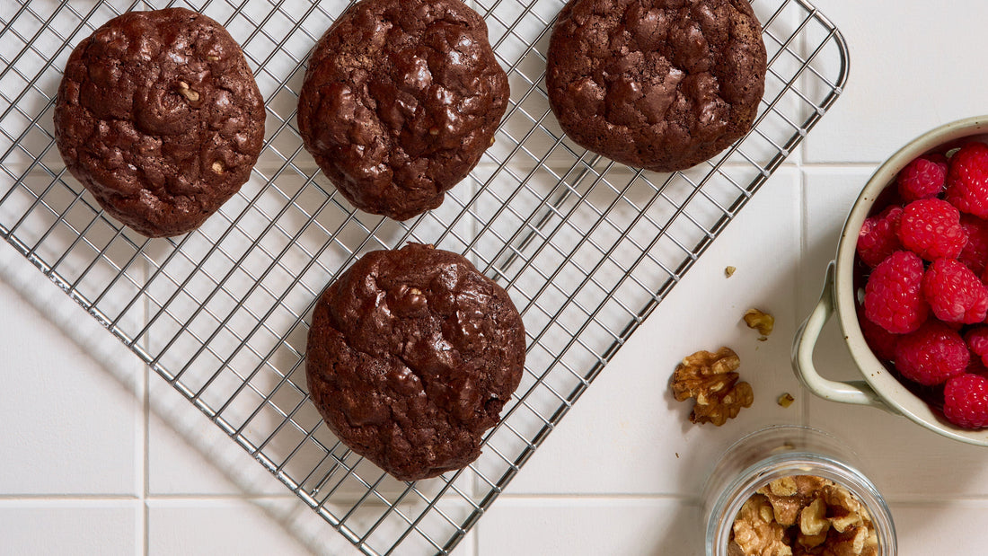 Fudgy Flourless Brownie Cookies cooling on a wire rack next to a bowl of fresh raspberries.
